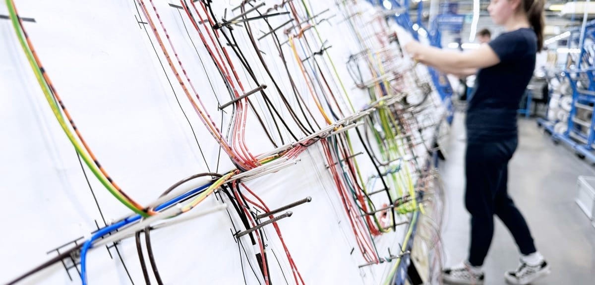 An electronics operator building a large wiring harness on a large looming board.