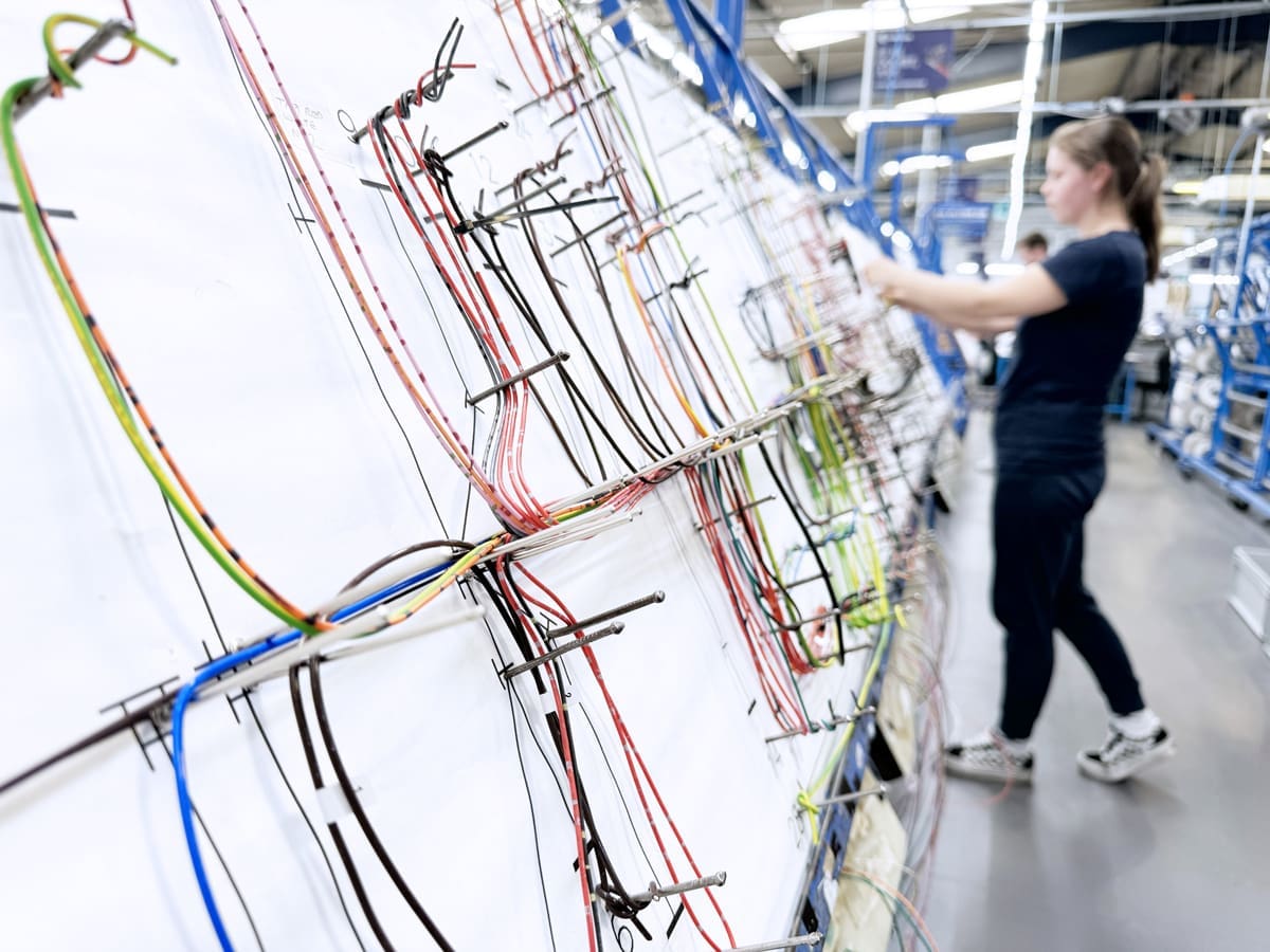 An electronics operator building a large wiring harness on a large looming board.