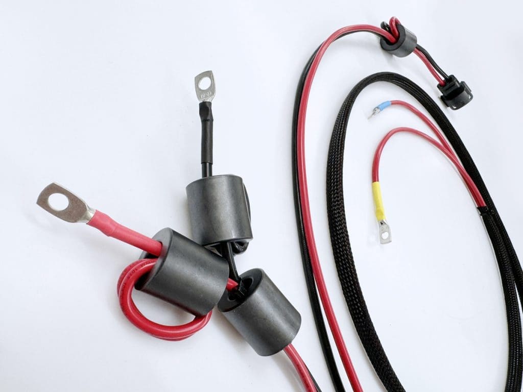 IoT cable assemblies looped on a desk. Red and black cables with various connectors.